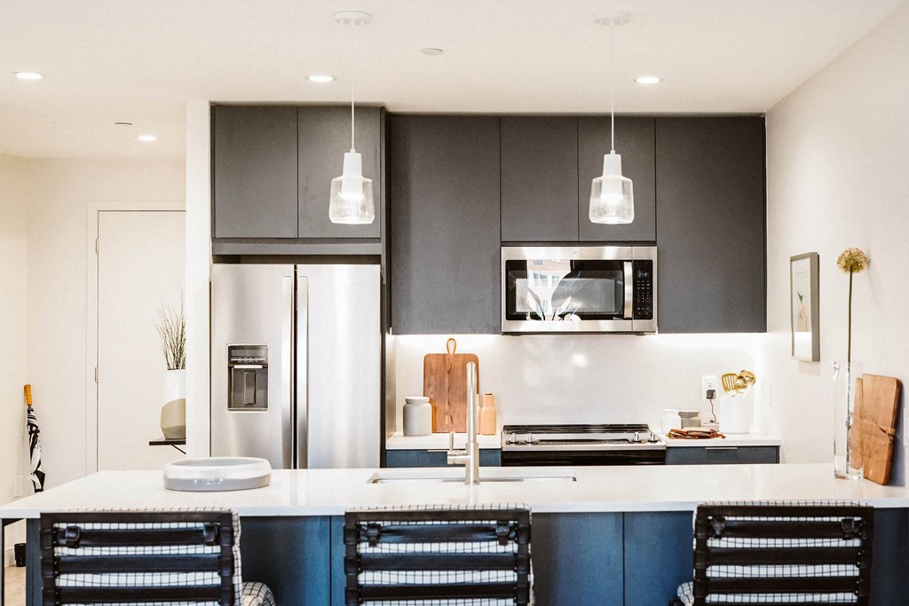a modern kitchen with black and white cabinets and a white counter top at The Lively, Jersey City
