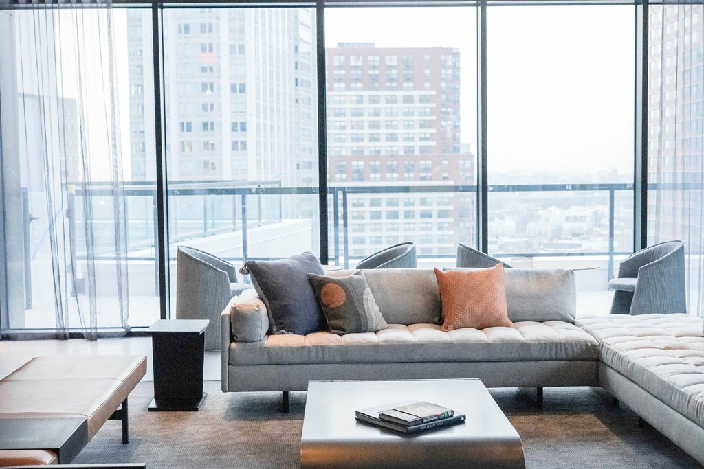 a living room with a couch and a table in front of windows at The Lively, Jersey City, NJ
