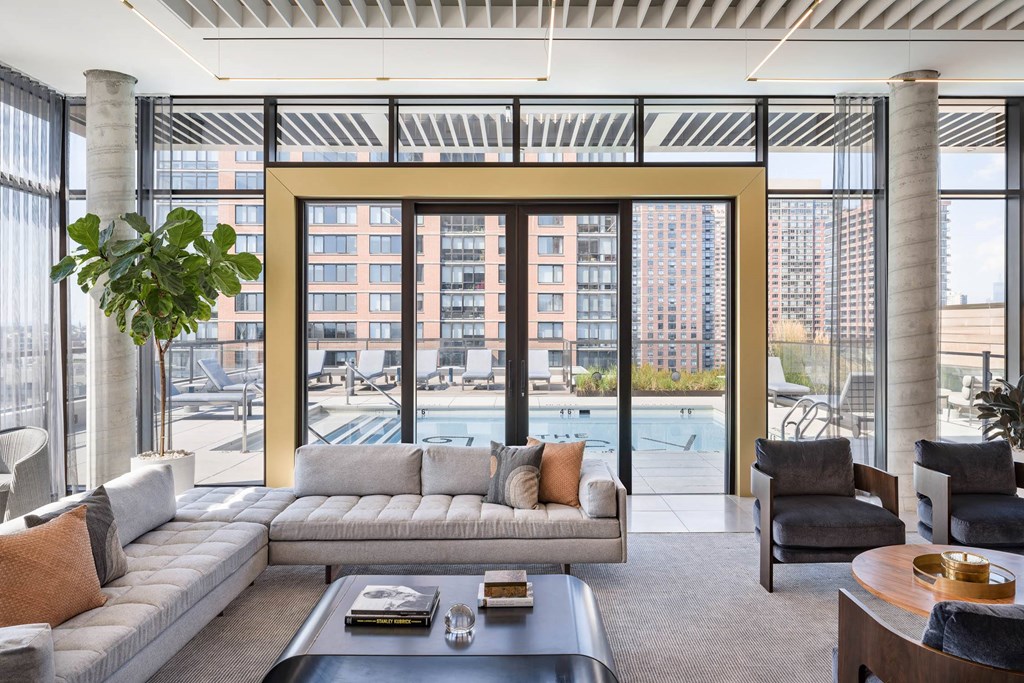 a room with couches and chairs and a view of a building at The Lively, Jersey City New Jersey