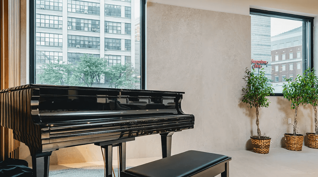 a piano in a living room next to a window