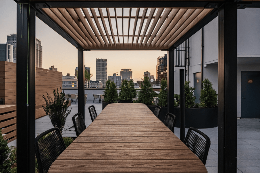 a long wooden table on a balcony with a view of the city