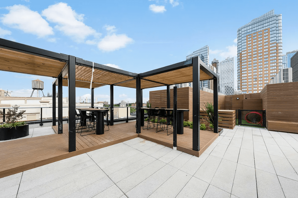 a roof deck with a table and chairs and a building in the background