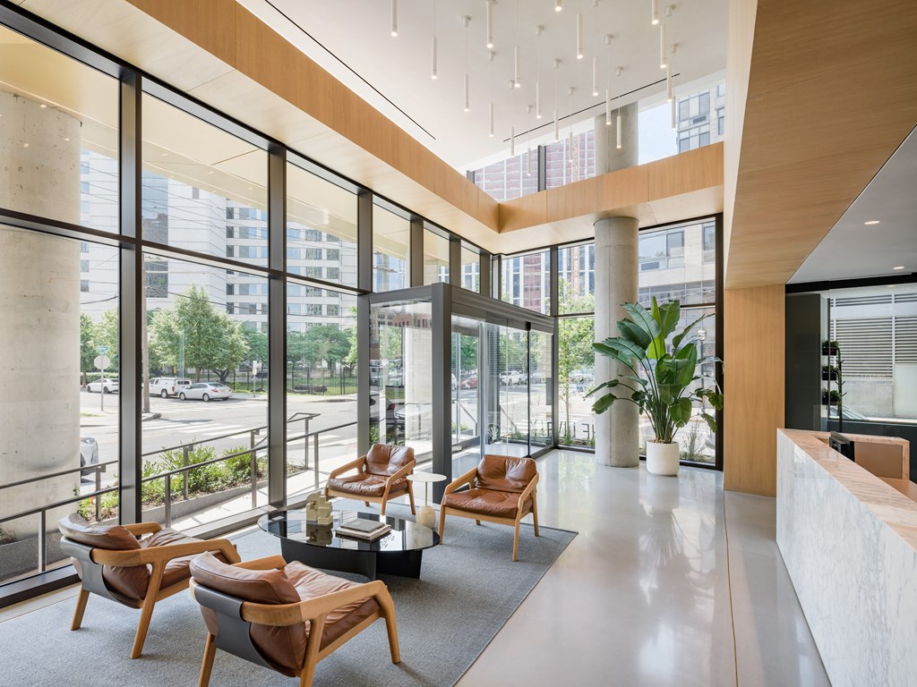 a lobby with chairs and a table in a building with large windows at The Lively, Jersey City, NJ