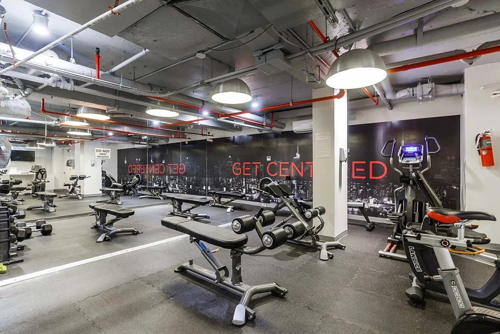 A gym with a variety of equipment including treadmills, stationary bikes, and weight machines.