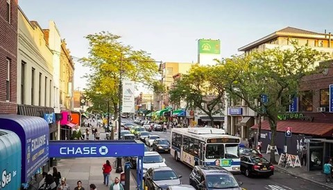 A busy street with cars, buses and pedestrians.