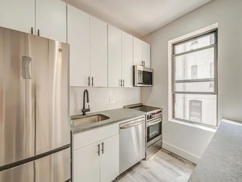 A kitchen with white cabinets and stainless steel appliances.