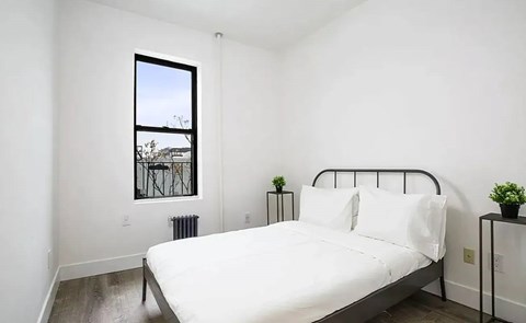 A bedroom with a large bed and a window overlooking a balcony.