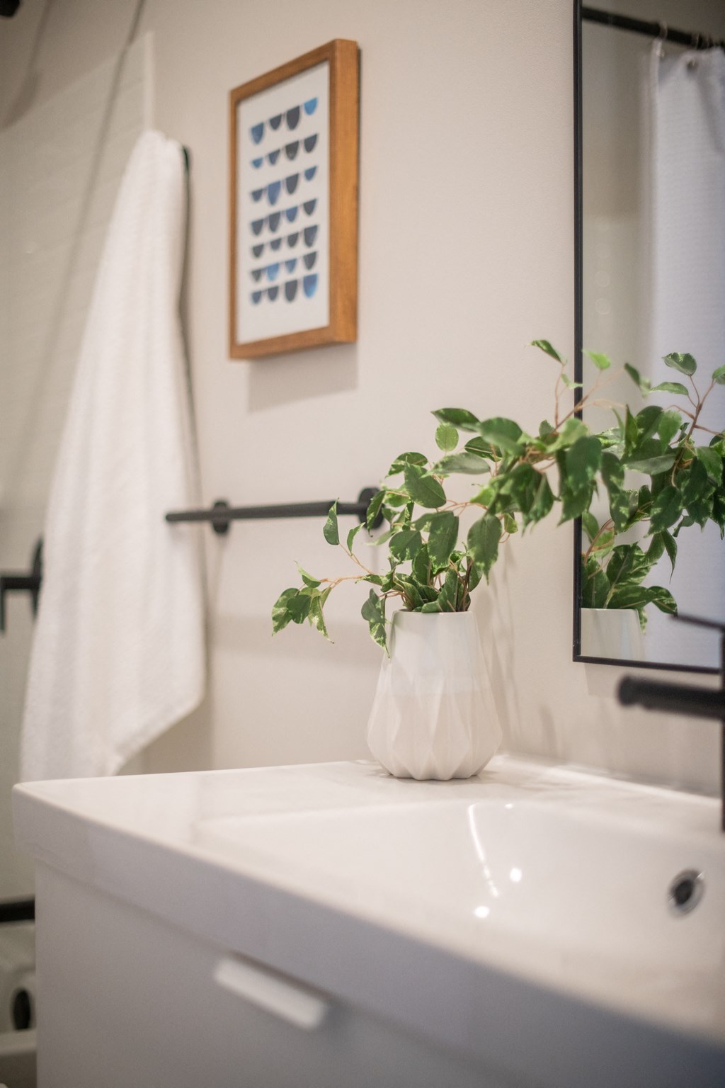 a bathroom with a white sink and a plant in a white vase at The 22 Apartments, St. Louis