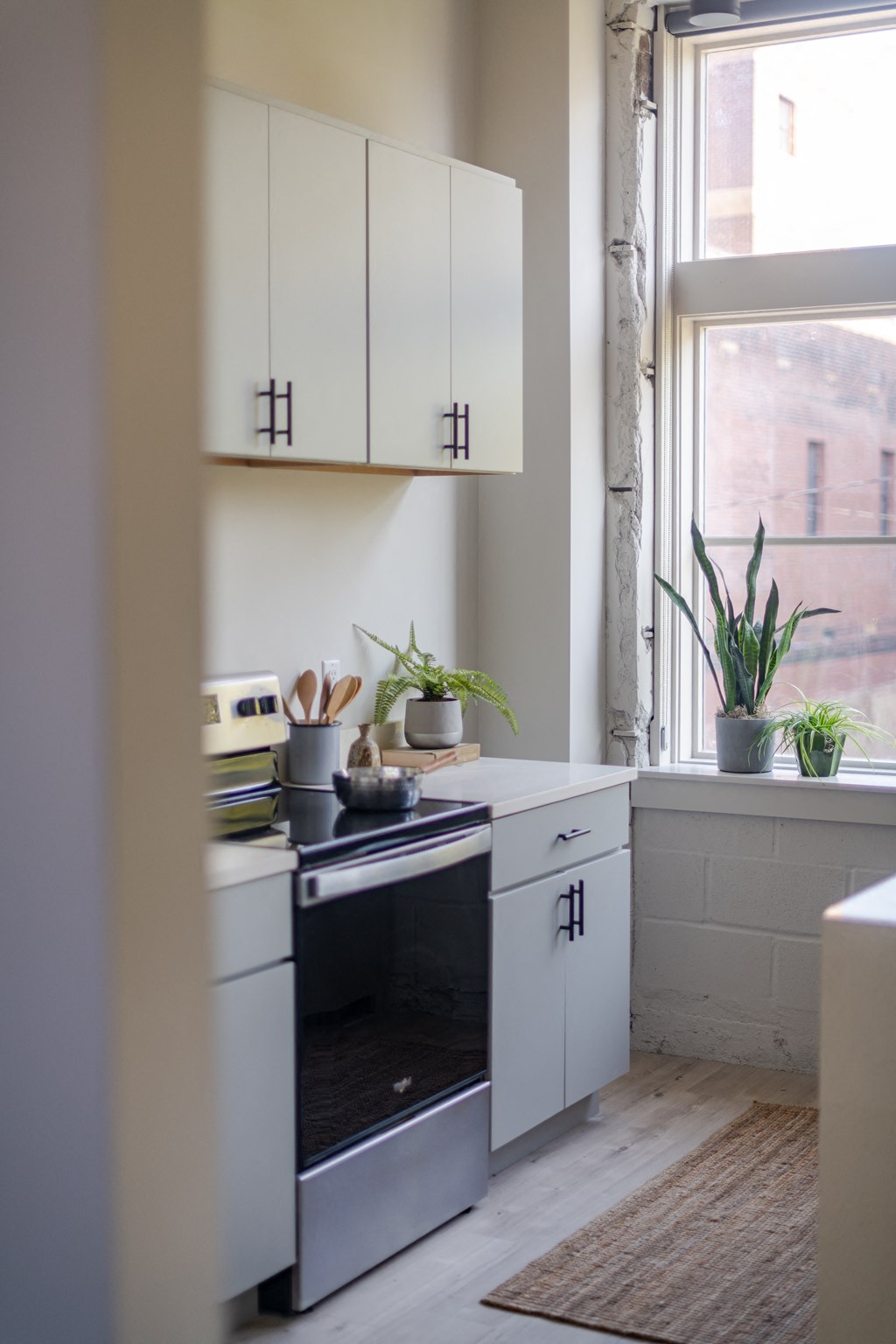 a kitchen with white cabinets and a window at The 22 Apartments, St. Louis, MO