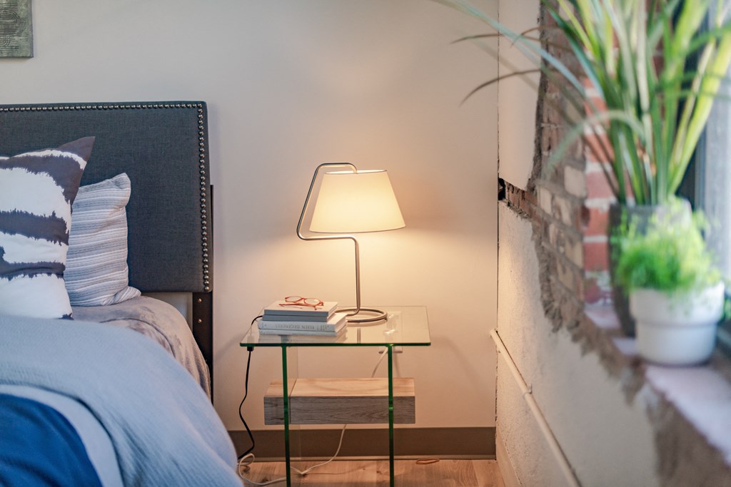 a nightstand with a lamp on it next to a bed at The 22 Apartments, St. Louis Missouri