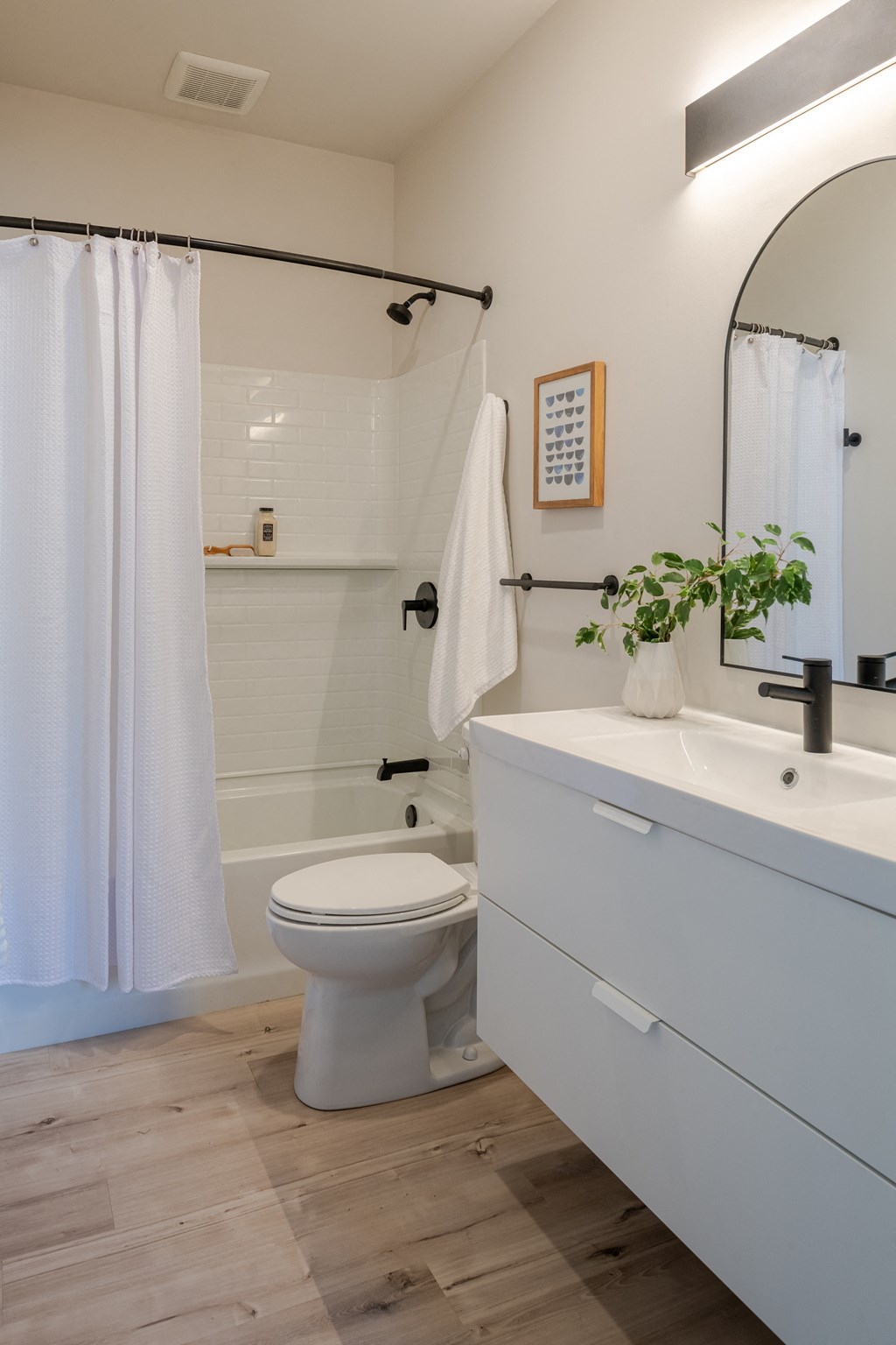 a bathroom with a white sink and toilet and a white shower curtain at The 22 Apartments, St. Louis, 63103