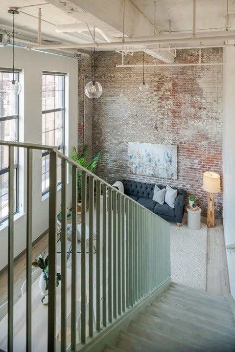 a living room with a brick wall and a couch and a staircase