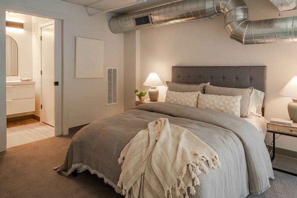 a bedroom with a bed and a exposed duct in the ceiling at The 22 Apartments, St. Louis, MO 63103