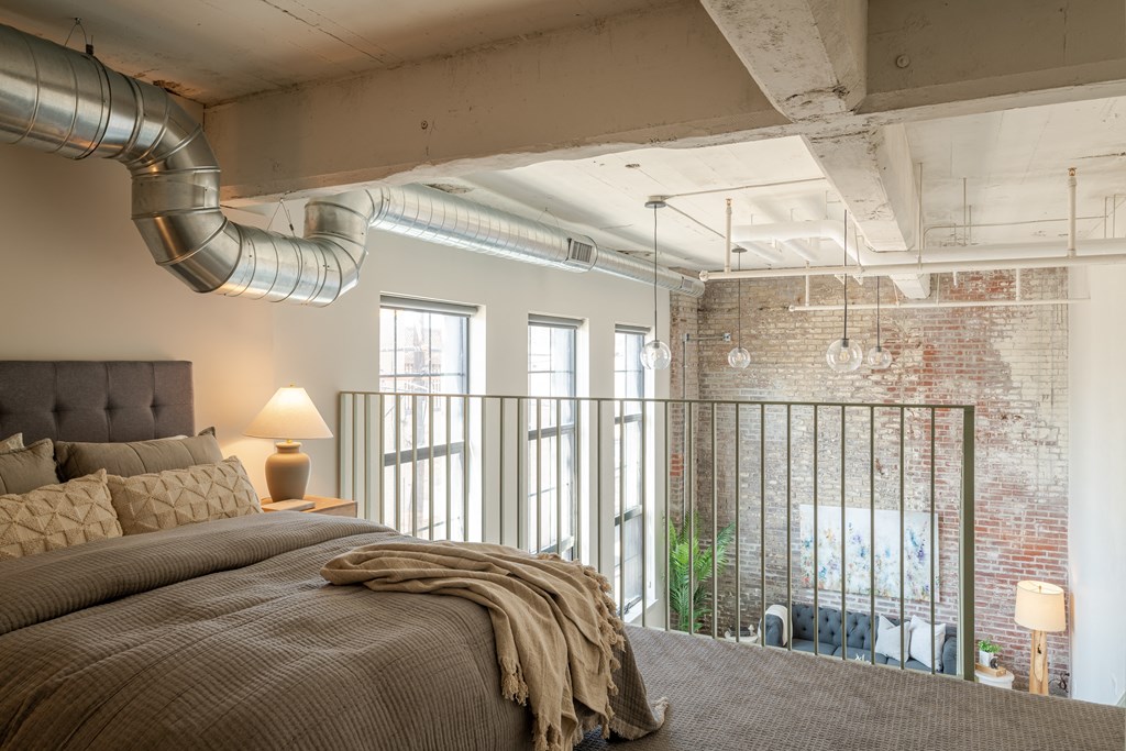 a bedroom with a bed and a exposed brick wall at The 22 Apartments, Missouri