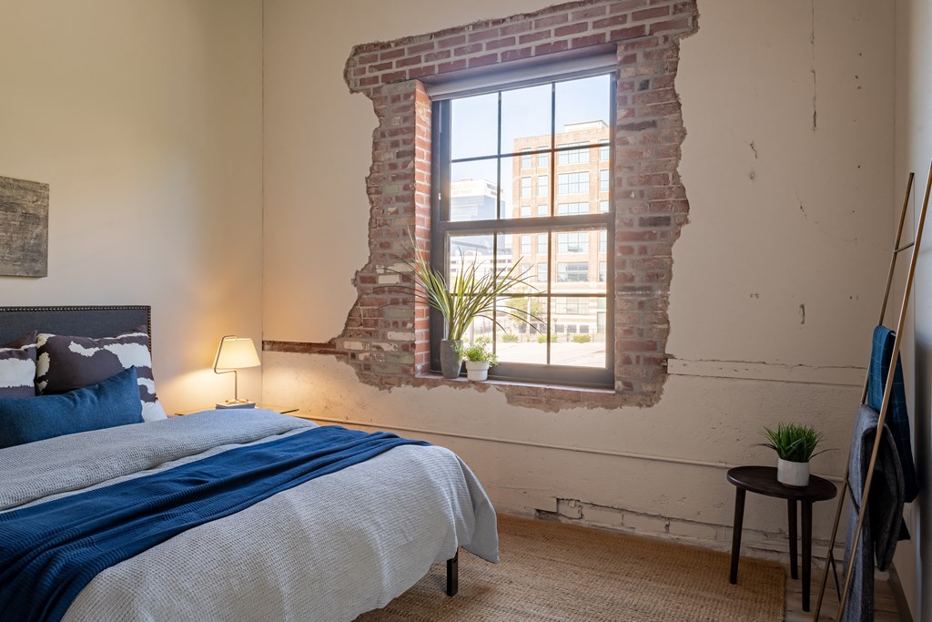 a bedroom with a exposed brick wall and a bed with a blue blanket at The 22 Apartments, Missouri, 63103