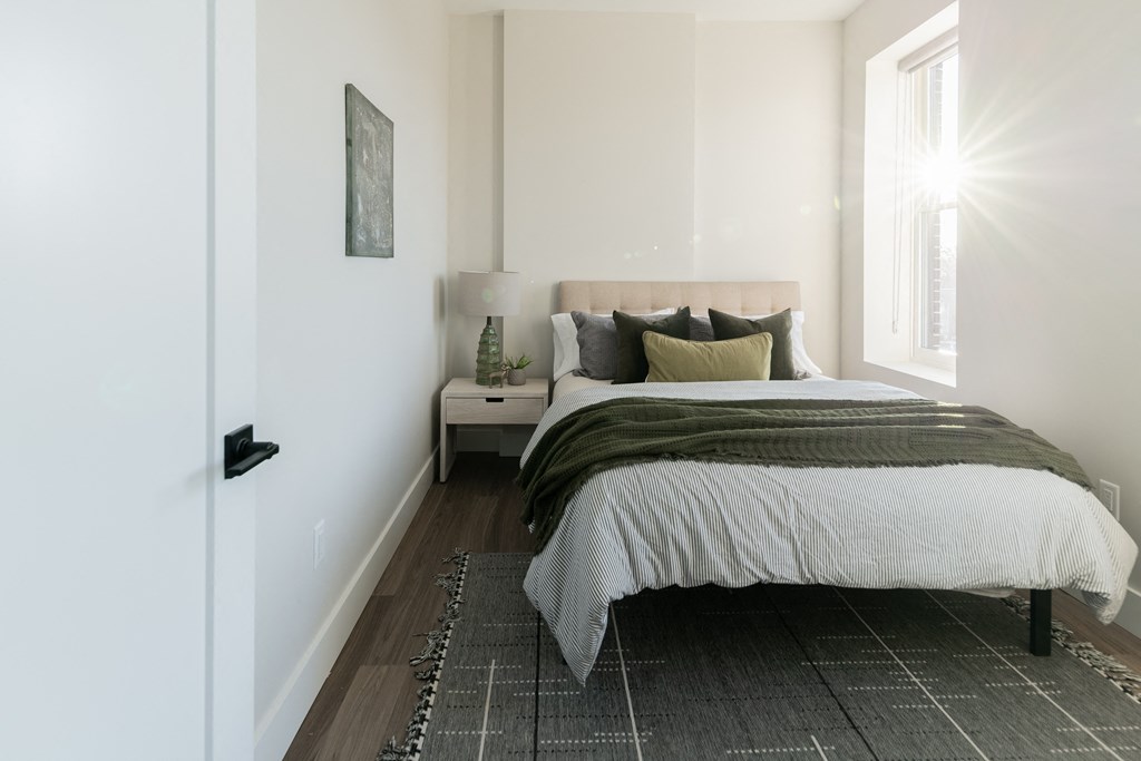 a bedroom with white walls and a bed with a blanket and pillows