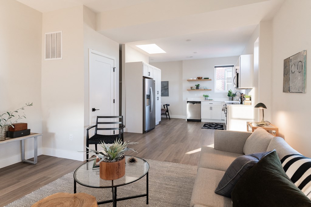 a living room with a couch and a coffee table and a kitchen in the background