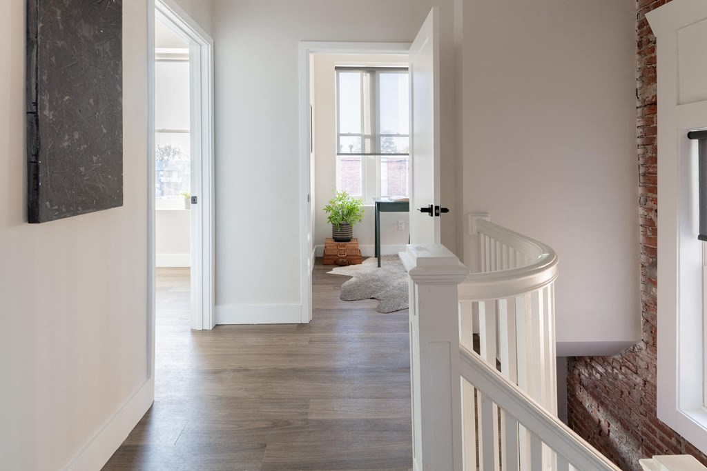 a view of a hallway with a staircase and a door to a living room