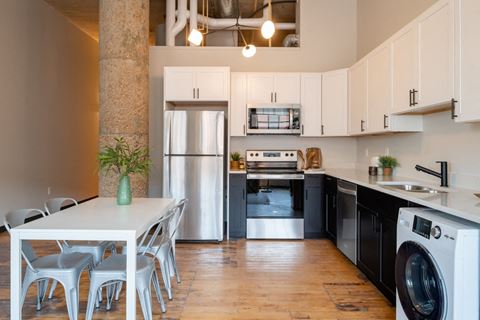 a kitchen with white cabinets and black and white appliances at The Draper, Missouri