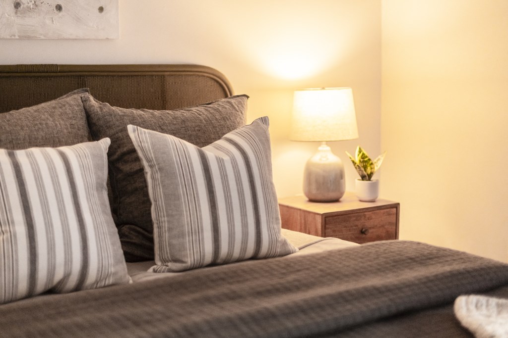 a bed with pillows and a nightstand with a lamp