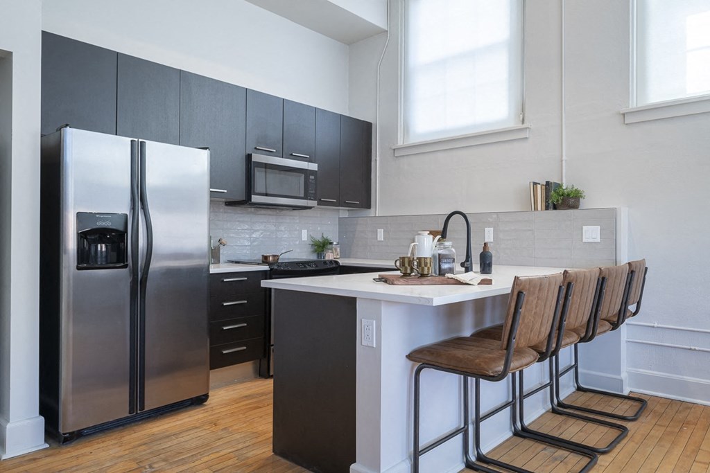 a kitchen with stainless steel appliances and a counter with three chairs
