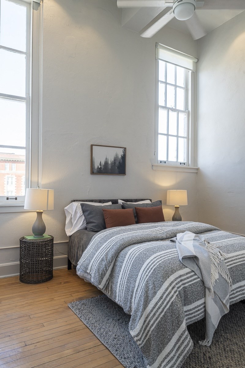 a bedroom with a bed and two windows