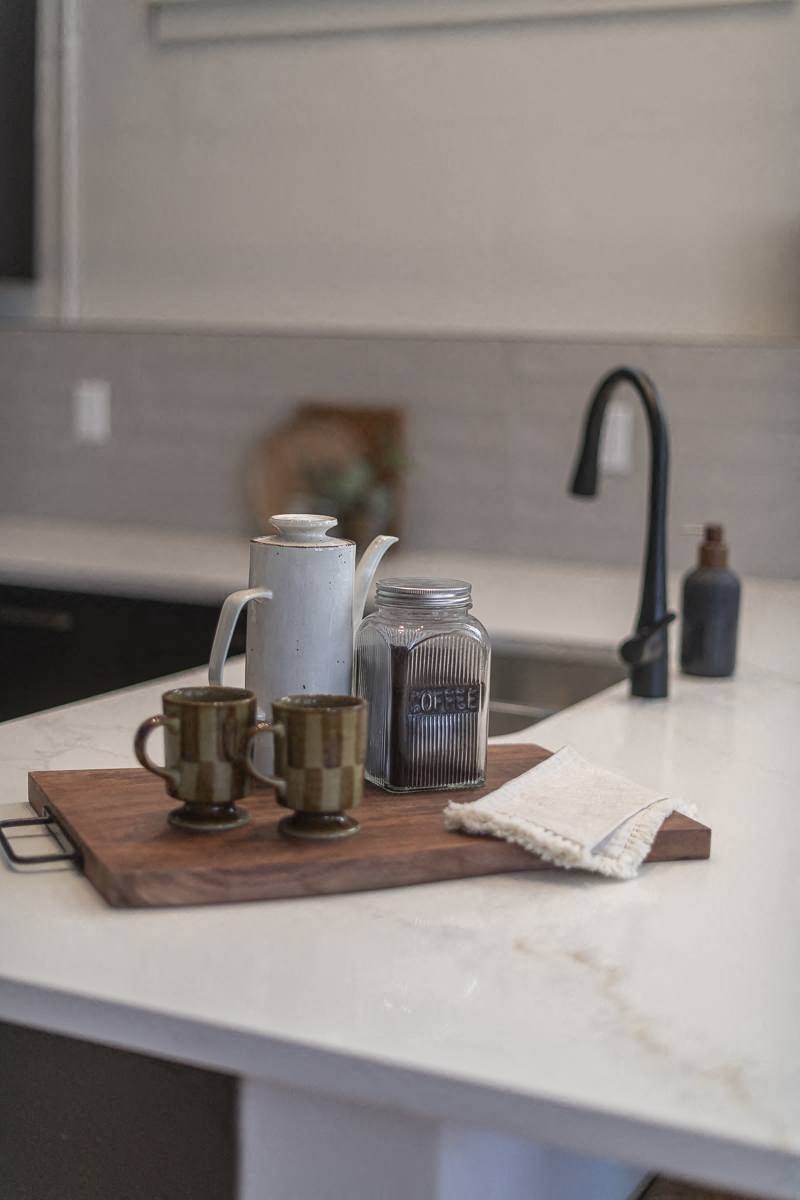 a kitchen counter with coffee cups on a cutting board