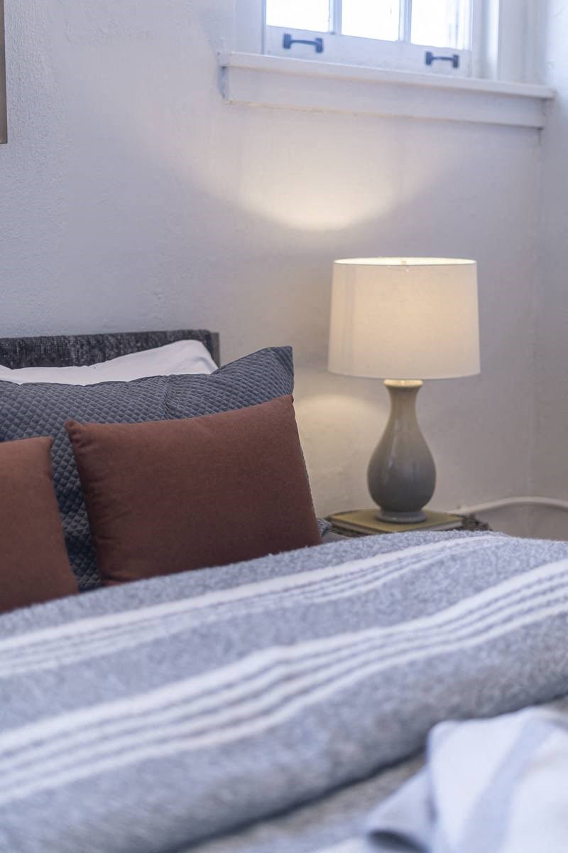 a bedroom with a bed with pillows and a lamp