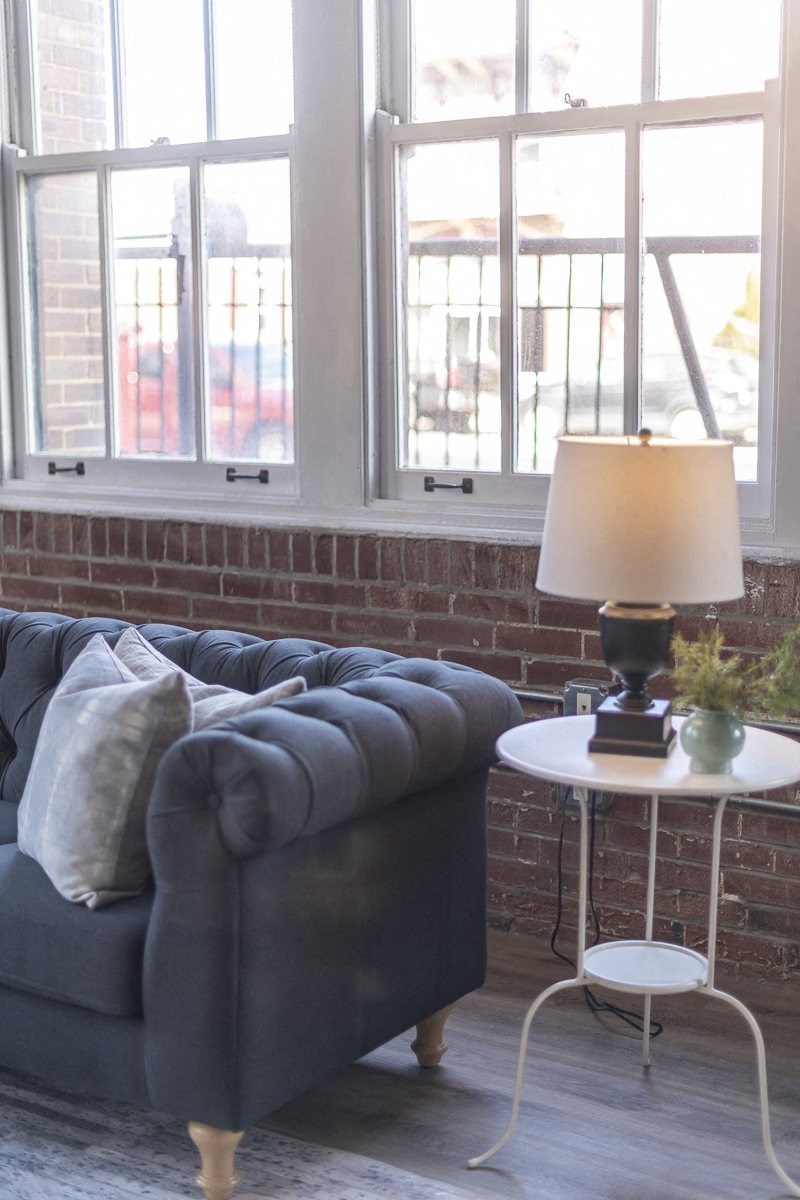 a living room with a couch and a table with a lamp
