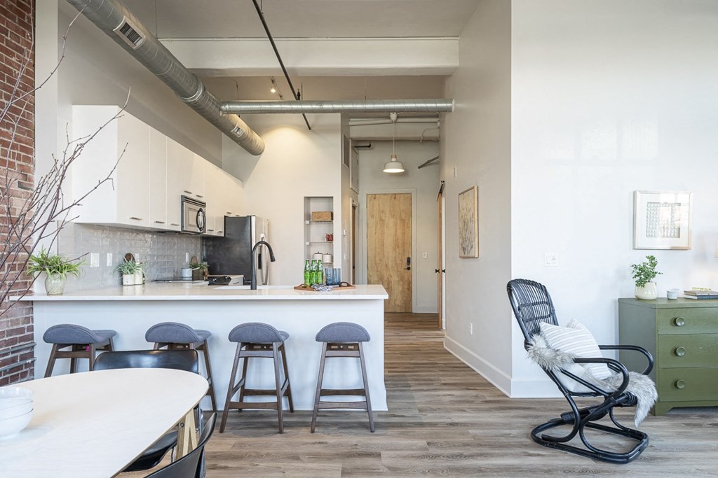 a kitchen and dining area with a white counter and bar stools