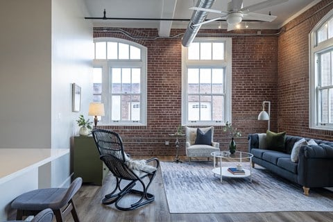 a living room with a brick wall and a couch and a chair