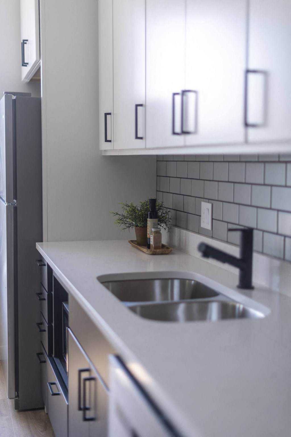 a white kitchen with white cabinets and a stainless steel sink