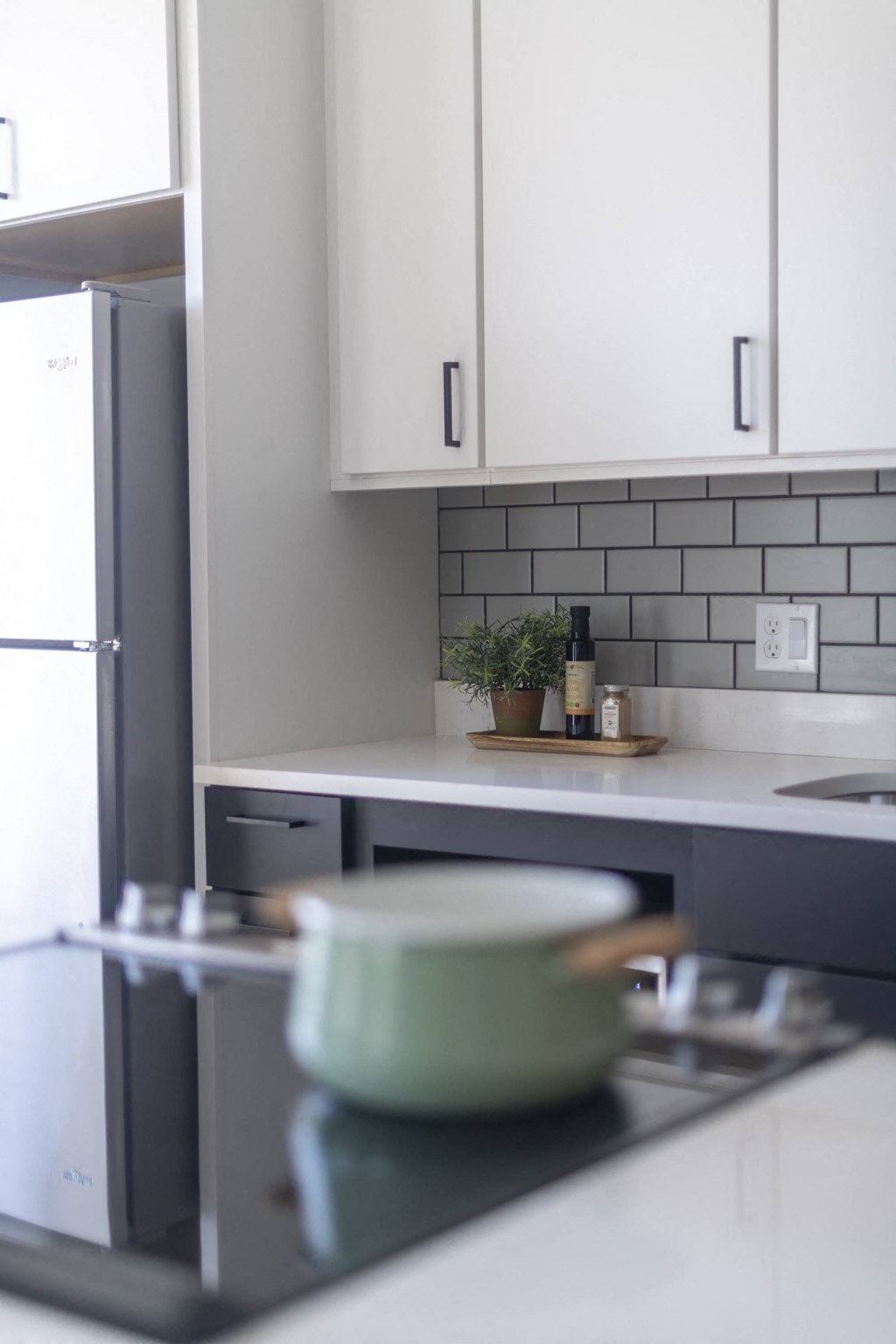a small kitchen with white cabinets and a pot on the stove