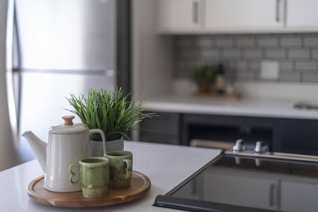 a kitchen counter with a tea kettle and plants on it