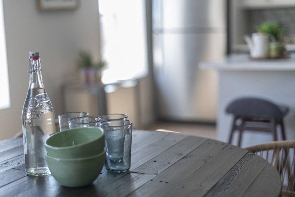 a wooden table with a bottle of water and glasses on it