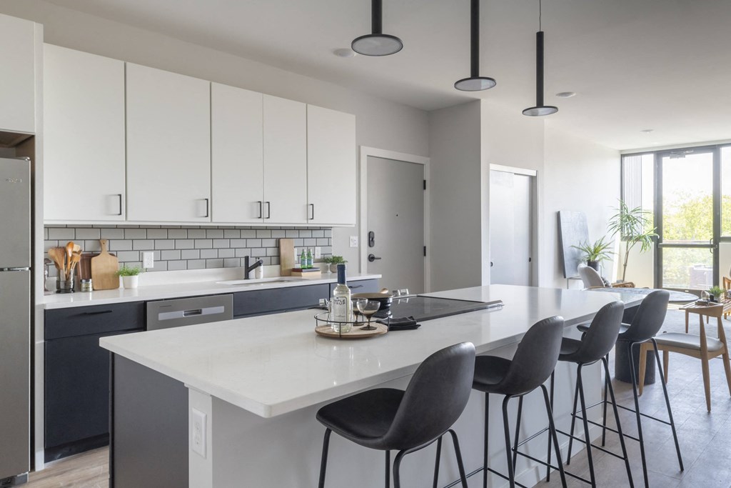 a kitchen with white counter tops and a large island with chairs