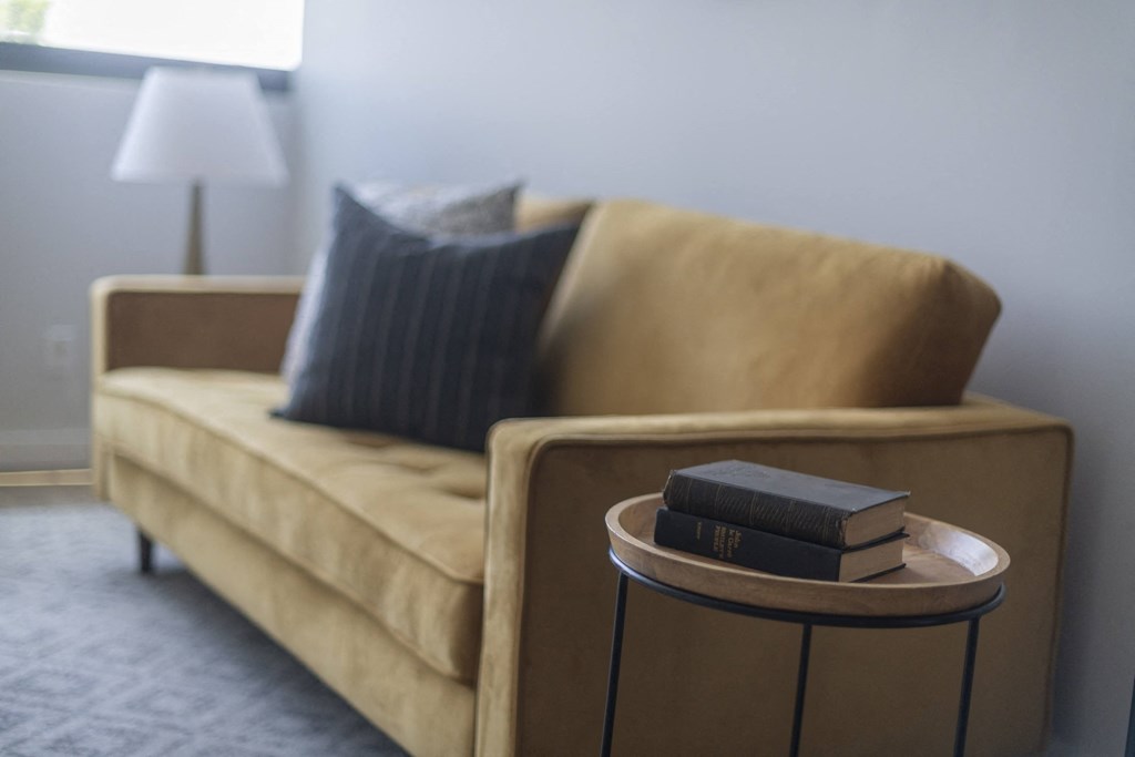 a couch in a living room with a book on a side table