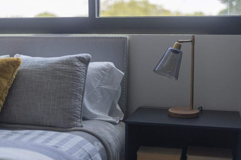 a bedroom with a bed and a nightstand with a lamp