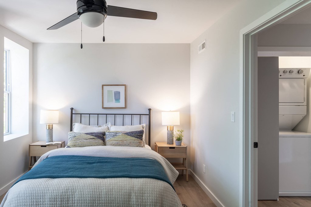 a small bedroom with a bed and a light on the wall
