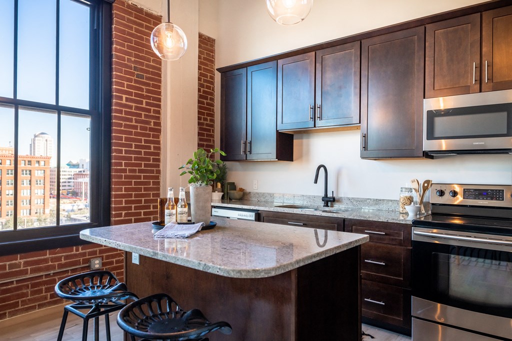 a kitchen with brown cabinets and a large window at The 22 Apartments, St. Louis Missouri