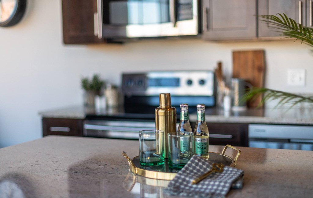 a kitchen island with a tray of wine bottles and a napkin on it at The 22 Apartments, St. Louis, MO 63103
