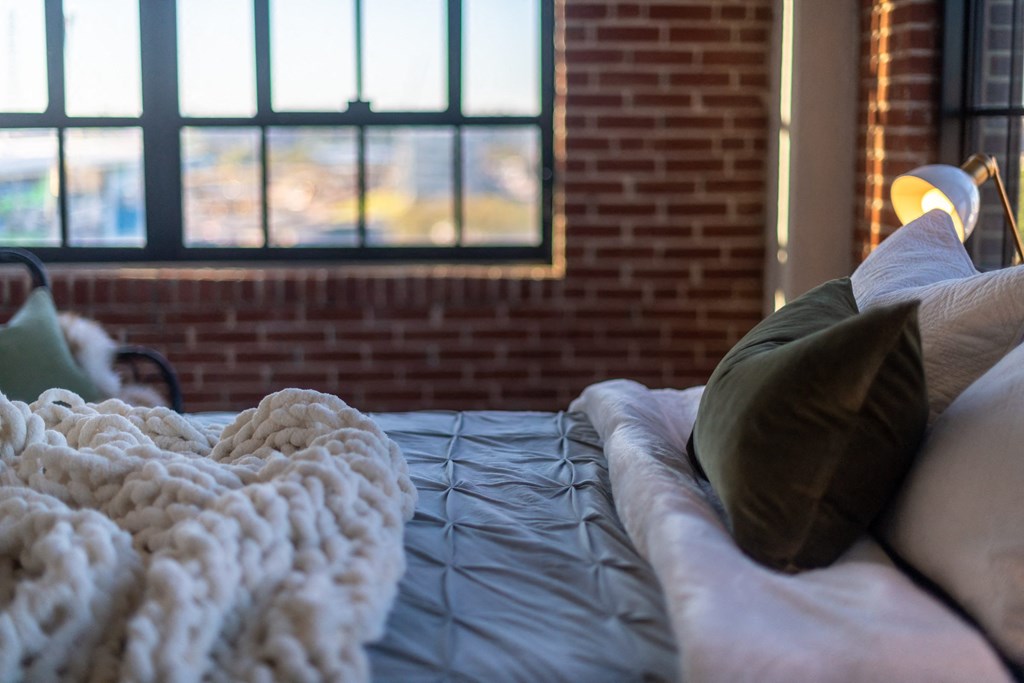 a bed with a blanket and pillows in front of a window at The 22 Apartments, Missouri, 63103