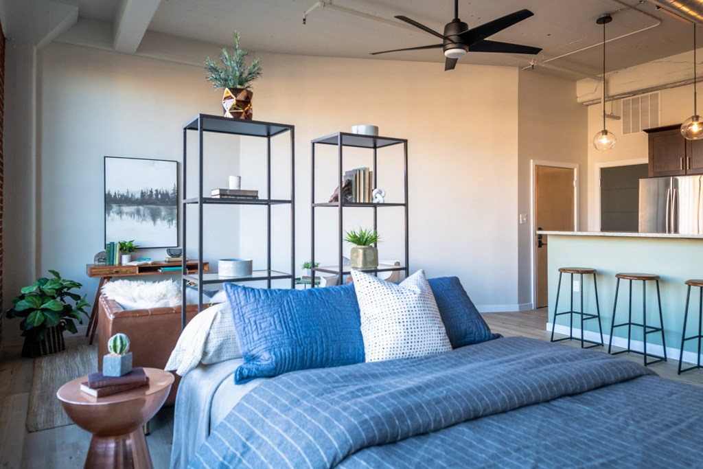 a bedroom with a bed and a kitchen in the background at The 22 Apartments, St. Louis, 63103