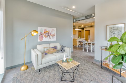 A living room with a white couch and a gold floor lamp.