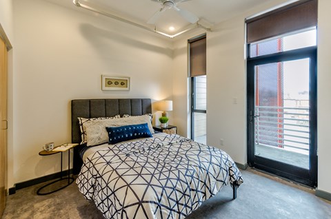 A bedroom with a patterned bedspread and a ceiling fan.