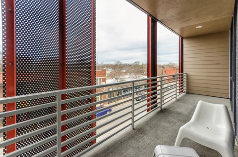 A balcony with a white chair and a metal railing.