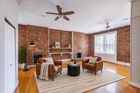 A living room with a brick wall and a fireplace.