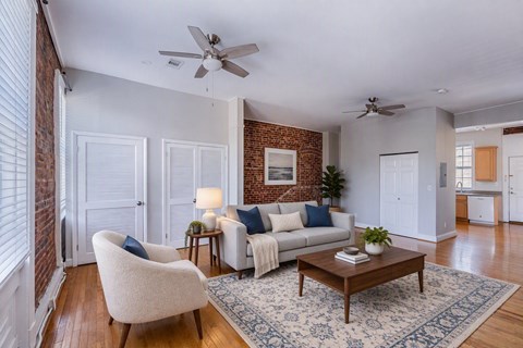 A living room with a white couch, a white chair, and a wooden coffee table.