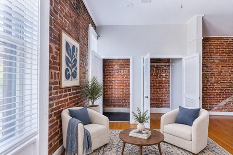 A living room with a brick wall and two chairs.
