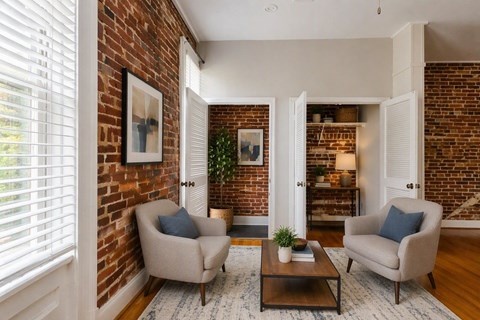 A living room with a brick wall and two chairs.